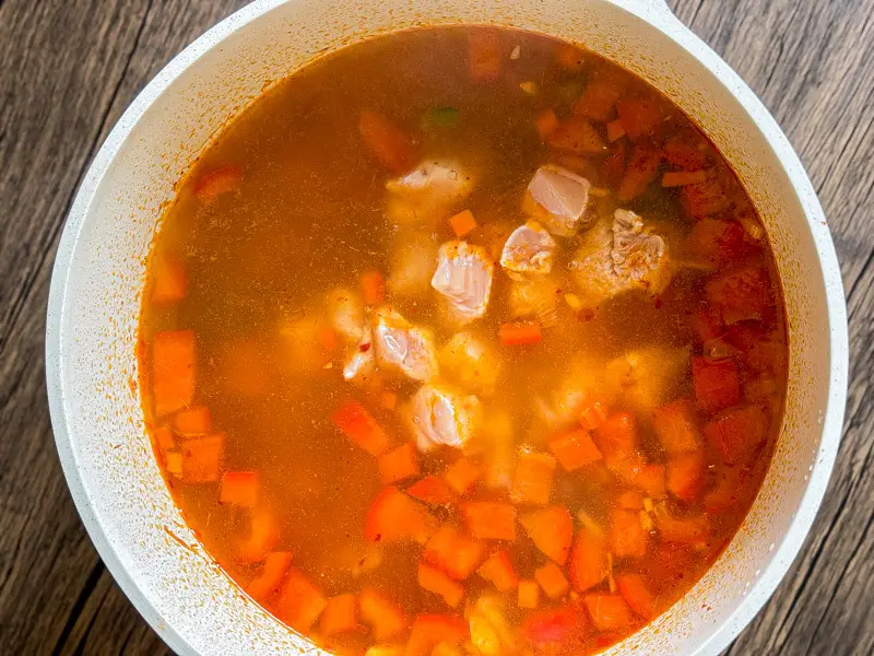 Chicken pieces simmering in red curry soup.