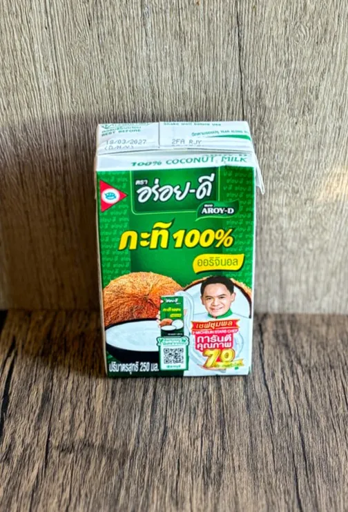 Aroy-D 100% coconut milk carton (250 ml) on wooden surface.