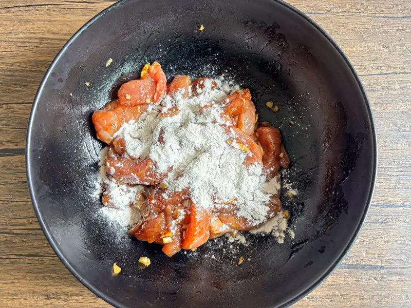Marinated pork with flour added in a bowl.