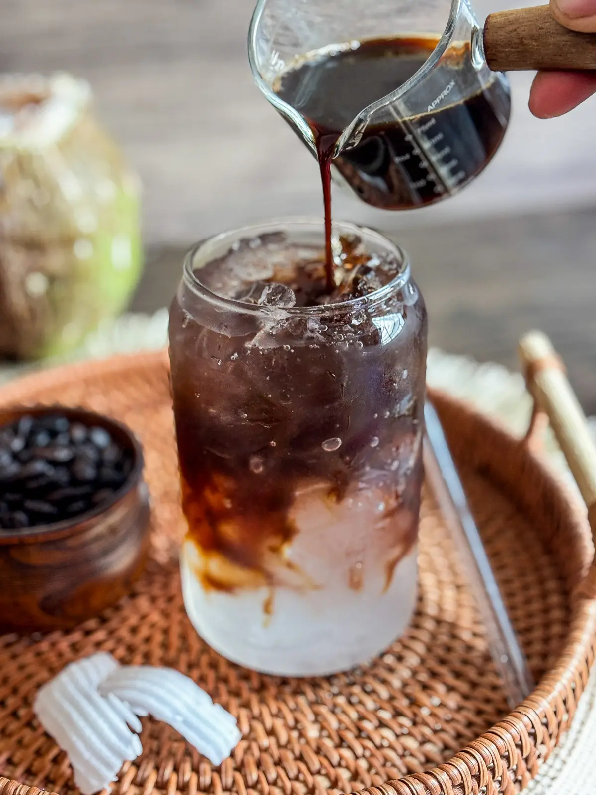 Pouring iced coconut water coffee in a glass jar.