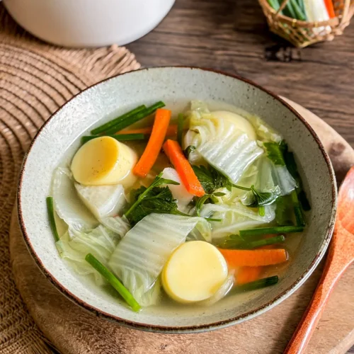 Vegetarian egg tofu soup with cabbage, carrot, daikon, and green onion in a clear broth.