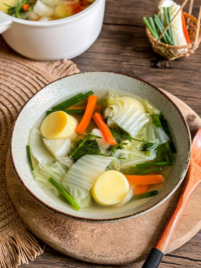 Vegetarian egg tofu soup with cabbage, carrot, daikon, and green onion in a clear broth.