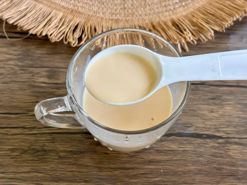 Sweetened condensed milk and evaporated milk mixed in a glass teacup.