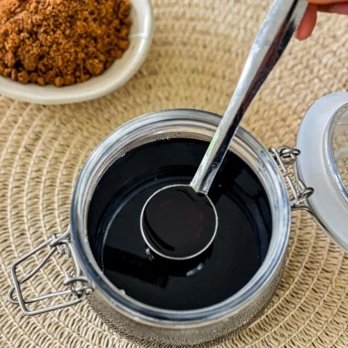 Hand holding spoon of brown sugar syrup ready to use.