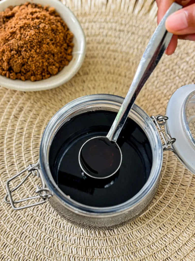 Hand holding spoon of brown sugar syrup ready to use.