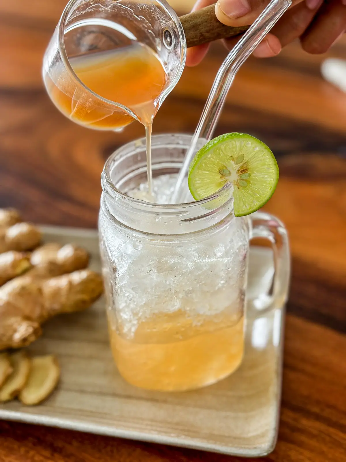 Pouring ginger syrup into a glass of ginger syrup soda.