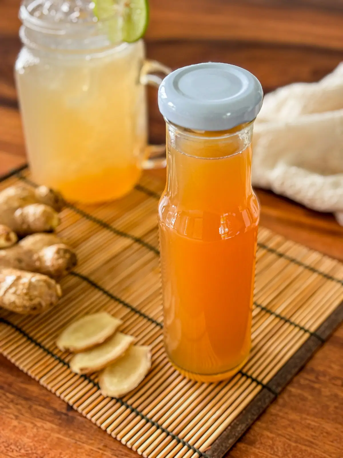Homemade ginger syrup in a glass bottle with fresh ginger slices.