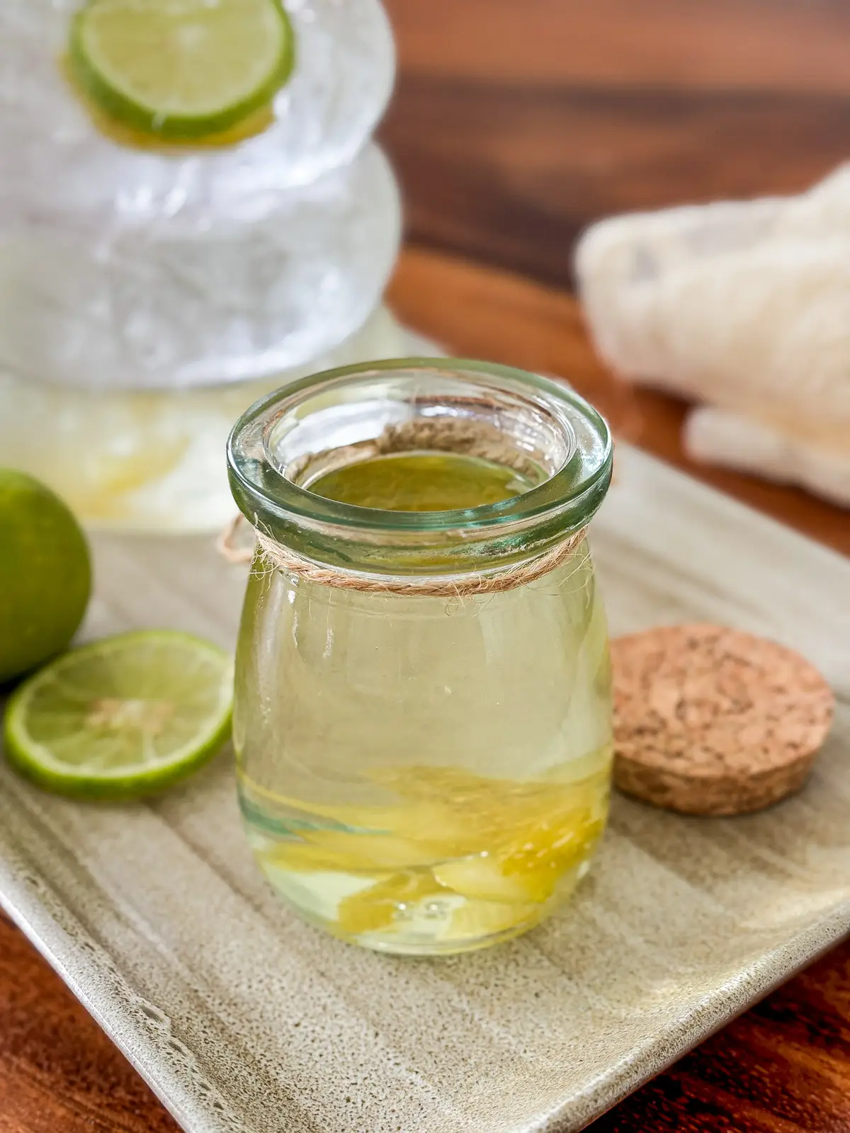 Homemade lime syrup in a glass jar with fresh lime slices.