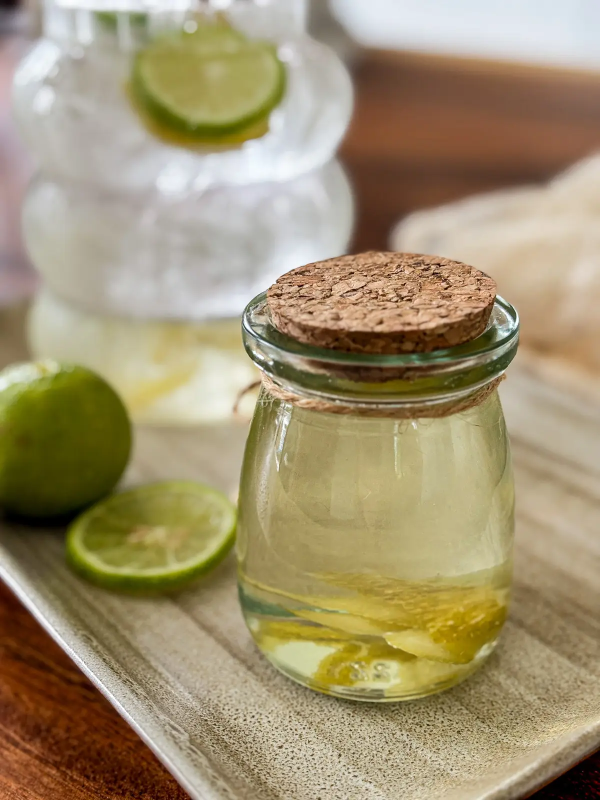 Homemade lime syrup in a glass jar with fresh lime slices.