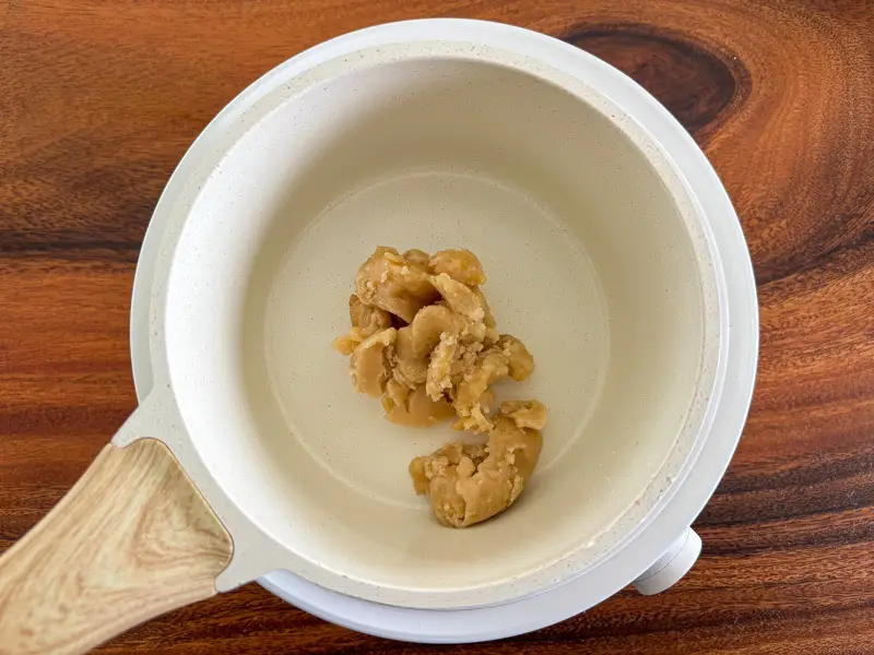 Palm sugar added to a saucepan.