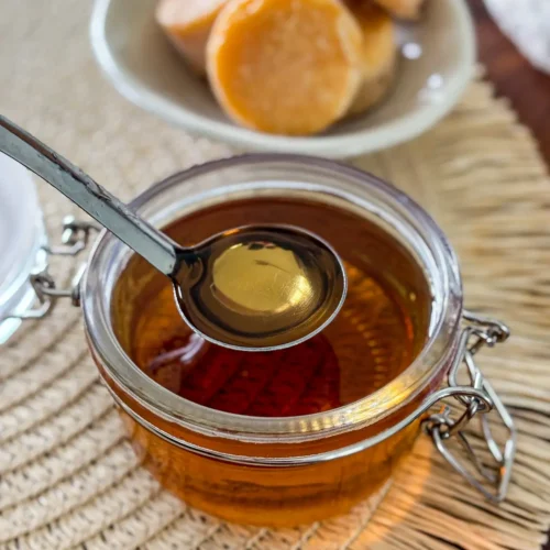 Homemade palm sugar syrup in a glass jar with a spoon.