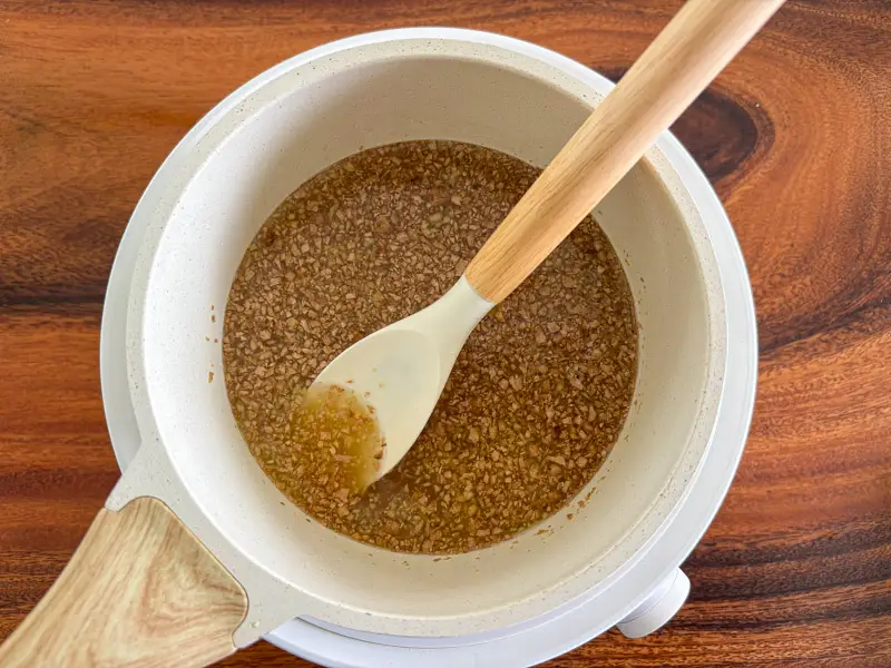 Ginger syrup simmering in a saucepan.