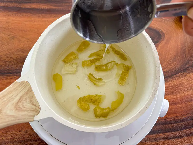 Lime peels simmering in syrup in a saucepan.