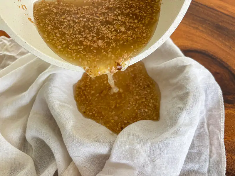 Straining ginger syrup through a cheesecloth.