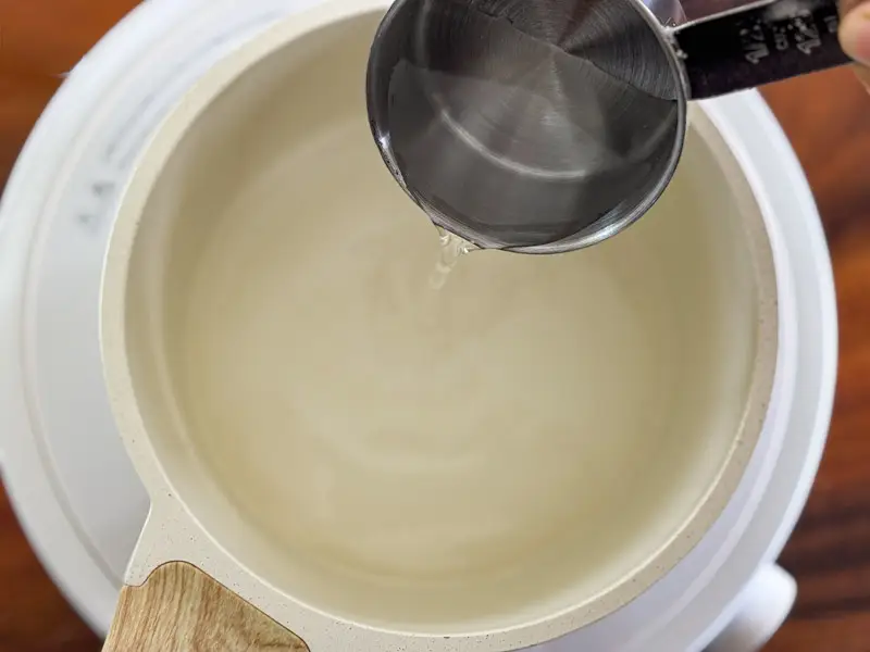 Pouring water into a saucepan to make a basic sugar syrup.